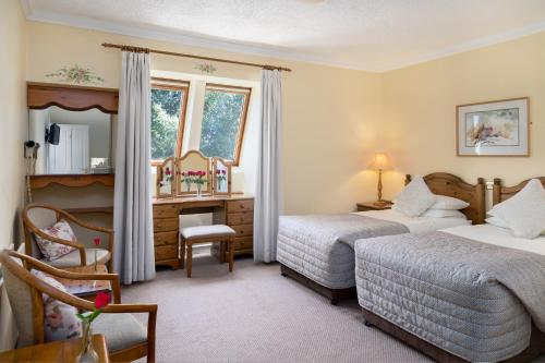 a hotel room with two beds and a chair at Kathleens Country House in Killarney