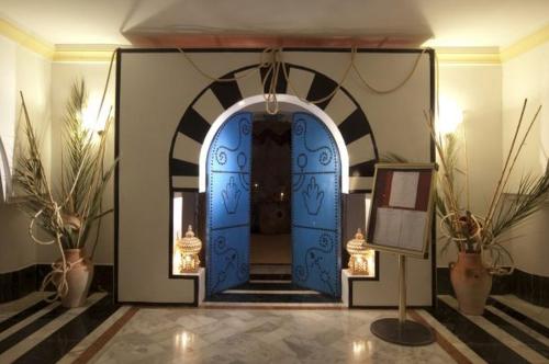 a blue door in a hallway with potted plants at El Mouradi Djerba Menzel in Midoun