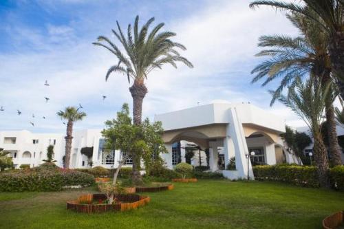 a building with palm trees in front of it at El Mouradi Djerba Menzel in Midoun