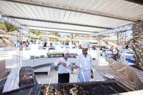 two chefs preparing food on a grill at a resort at El Mouradi Djerba Menzel in Midoun