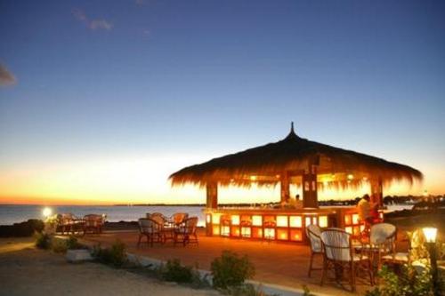 a restaurant with a straw umbrella and chairs on the beach at El Mouradi Djerba Menzel in Midoun