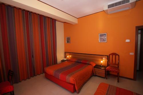 a bedroom with a bed with orange walls and a chair at Hotel Naxos B&B in Alba Adriatica