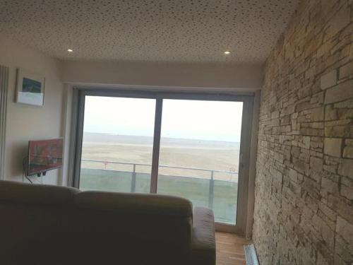 a living room with a couch and a large window at Appartement Knokke-Heist in Knokke-Heist