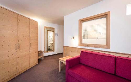 a living room with a red couch and a window at Villa Tony - Small Romantic Hotel in Corvara in Badia