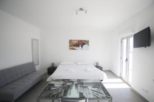 a white room with a bed and a glass table at Guest House Lovely Swan in Lagos