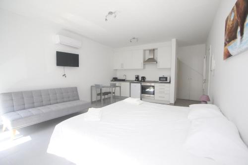 a white bedroom with a large bed and a couch at Guest House Lovely Swan in Lagos