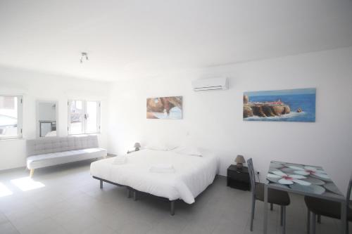 a white bedroom with a bed and a table at Guest House Lovely Swan in Lagos