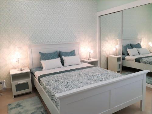 ein weißes Schlafzimmer mit 2 Betten und Spiegeln in der Unterkunft T1 PraiaMar RC com Ar-Condicionado in Quarteira