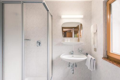 a white bathroom with a sink and a shower at Pension Merisana in Colfosco