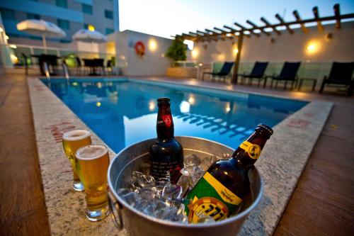 duas garrafas de cerveja num balde ao lado de uma piscina em Go Inn Hotel Aracaju em Aracaju