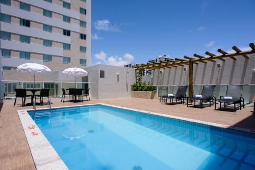 uma piscina com cadeiras e guarda-sóis ao lado de um edifício em Go Inn Hotel Aracaju em Aracaju