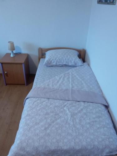 a bed with a blue comforter and a night stand at Kuca za odmor Sarcevic in Prozor