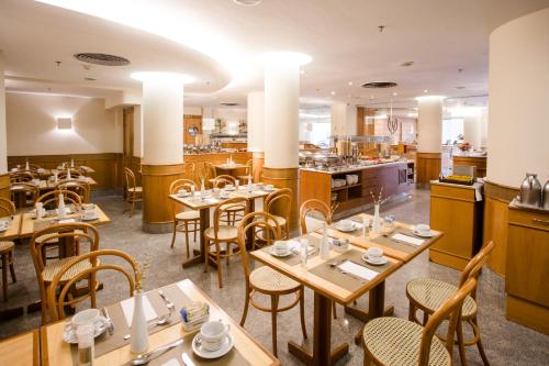 a restaurant with wooden tables and chairs and a kitchen at Windsor Martinique Copacabana in Rio de Janeiro