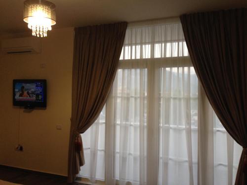 Habitación con ventana con cortinas y TV. en Hotel Real, en Ishull-Lezhë
