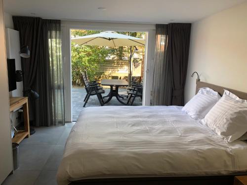 ein Schlafzimmer mit einem Bett und einem Tisch mit einem Sonnenschirm in der Unterkunft Casa del Cisne 2 in Zandvoort