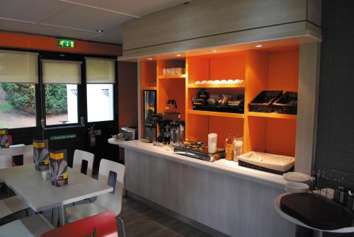 a restaurant with orange walls and a counter with a table at The Crossway Hotel, Part of AG Collection in Coventry