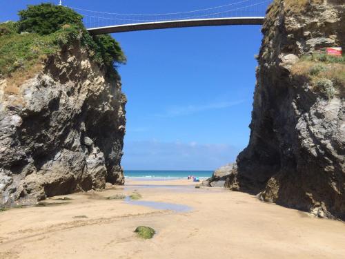 a bridge over a sandy beach with people on the beach at Palace Surf Lodge in Newquay