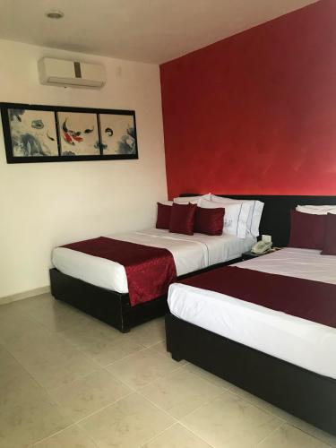 two beds in a hotel room with red walls at Quinta Santa Anita in Playa del Carmen