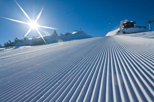 a snow covered slope with the sun in the background at ImPuls | aparts in Schladming