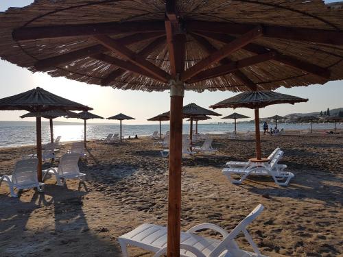 a group of chairs and umbrellas on a beach at Villa Feliks in Ljubač