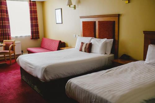 a hotel room with two beds and a chair at Inn On The Coast in Portrush