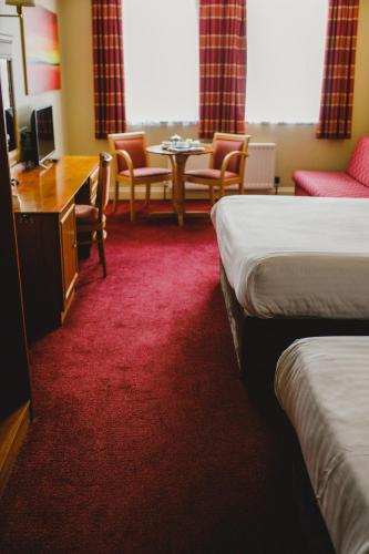 a hotel room with two beds and a desk and chairs at Inn On The Coast in Portrush