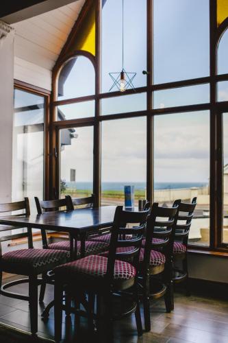 a dining room with a table and chairs and windows at Inn On The Coast in Portrush