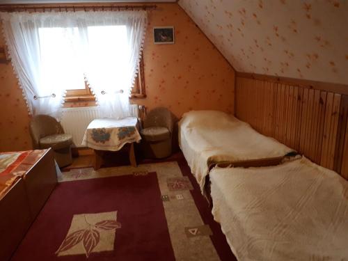 a small room with two beds and a window at Olsik in Białowieża