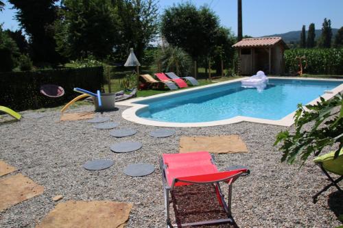 une chaise rouge assise à côté de la piscine dans l'établissement ancienne ferme rénovée, à Upie