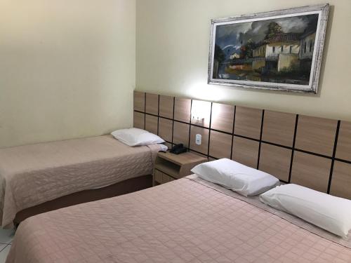 a room with two beds and a picture on the wall at Cafe e Almoço Hotel Thermas da Affego in Caldas Novas