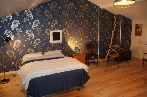 une chambre avec un lit avec un papier peint bleu et or dans l'établissement ancienne ferme rénovée, à Upie