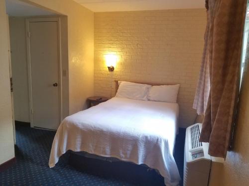 a hotel room with a white bed and a window at Motel 6 Tallahassee, FL North Monroe in Tallahassee