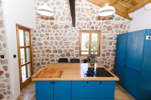 a kitchen with blue cabinets and a stone wall at Apartment Komoda in Kaprije