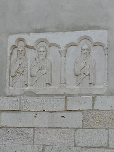 a stone wall with three statues on it at Diadumeno Superior Apartment in Venosa