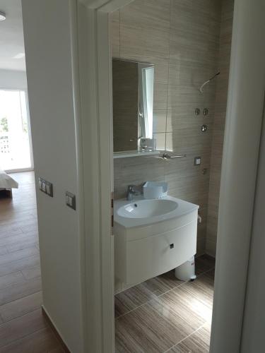 W łazience znajduje się biała umywalka i lustro. w obiekcie Apartmani Ivković w mieście Funtana