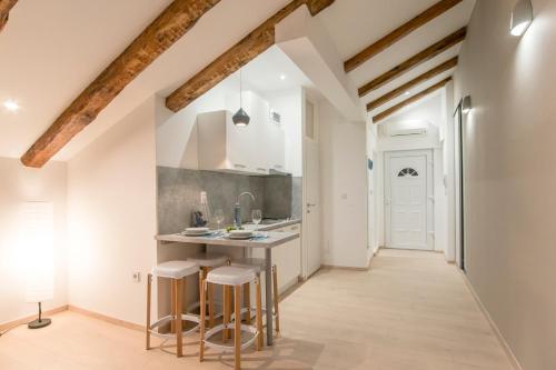 a kitchen with white walls and wooden beams at Fran Center Apartments (Square) in Pula