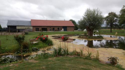 ein Gebäude mit einem Teich vor einem Haus in der Unterkunft chambre coin nature in Fromelles