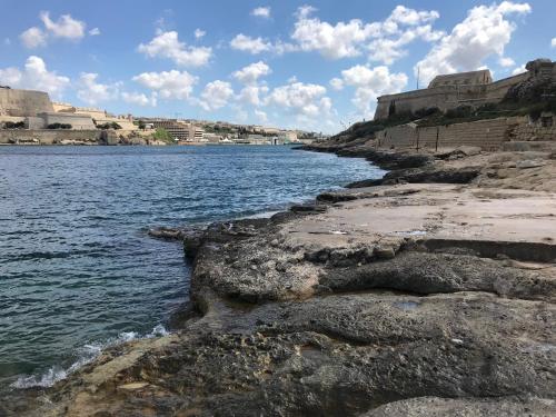 a view of a body of water with rocks at Pilgrim's Rest Apartments in Il-Gżira