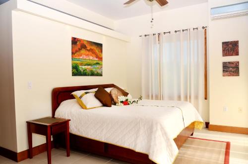 a bedroom with a bed and a painting on the wall at The Villas at Cocoplum in Placencia Village