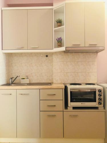a kitchen with white cabinets and a microwave at Lovely Apartments in Patra