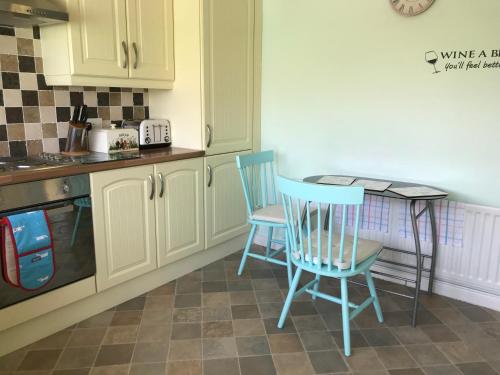 a kitchen with two blue chairs and a table at Suntana at Causeway Coast and Glens in Coleraine