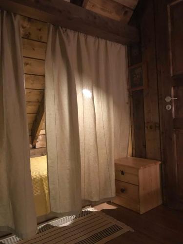a bedroom with a bed with a curtain and a dresser at Tahkuna Forest House in Kõrgessaare