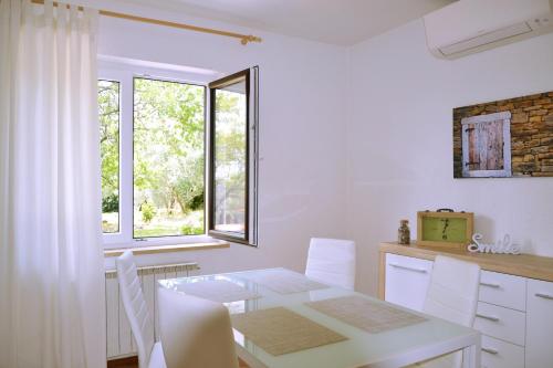 a white kitchen with a table and white chairs at Apartment Istrian view in Šmarje