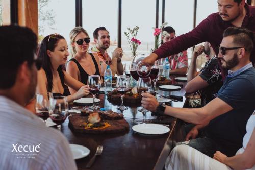 un grupo de personas sentadas alrededor de una mesa con copas de vino en Vinos Xecué, en Ensenada