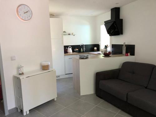 ein Wohnzimmer mit einer Couch und einer Uhr an der Wand in der Unterkunft Mazet « Domaine de la pinède » in Le Lavandou