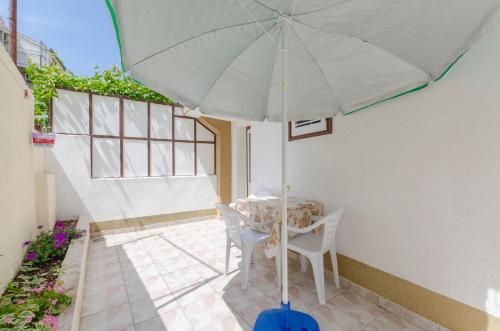 a table and chair with an umbrella on a patio at Apartments Visnja in Primošten