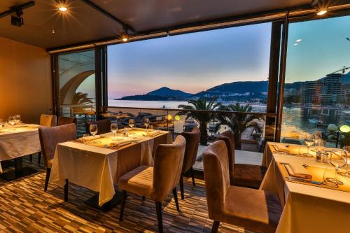 a restaurant with tables and chairs and a large window at Hotel Zeta in Budva