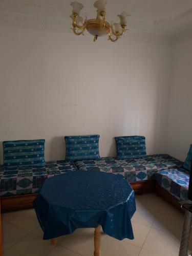 Cette chambre comprend un lit avec des oreillers bleus et une table. dans l'établissement joli appartement 4 chambres, à Oujda