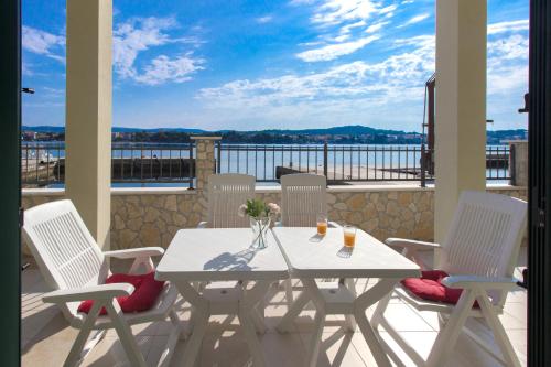 a white table and chairs on a balcony with a view at Riva in Krapanj