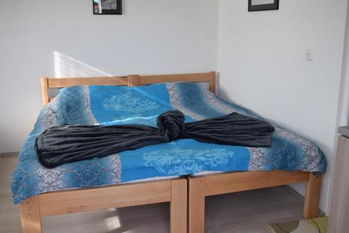 a bed with a blue comforter and a black robe on it at NULI apartments in Kruševo